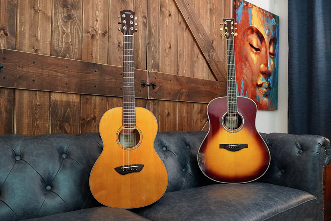 Two Yamaha TransAcoustic guitars resting on a leather couch.