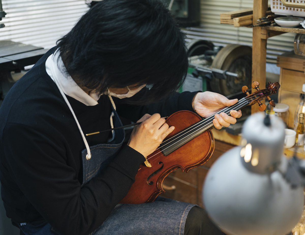 A luthier works on restoring an antique violin in a workshop.