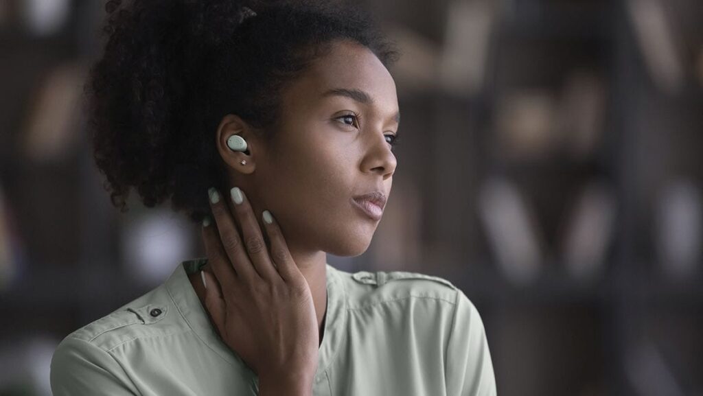 A young woman wearing a pair of earbuds.