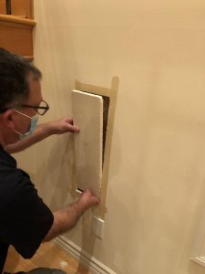 Closeup of man removing a cutout piece of drywall.