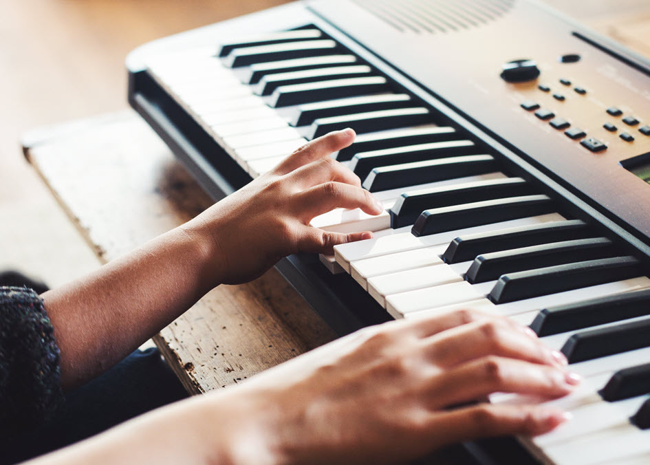 Closeup of someone's hands playing an electronic piano keyboard.