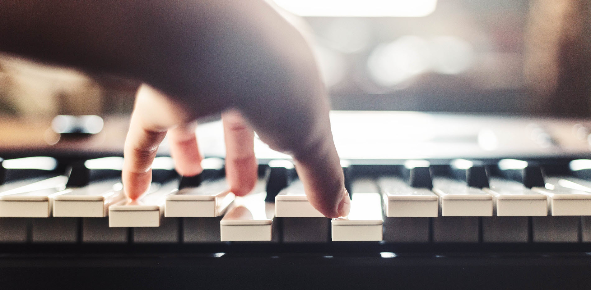 Closeup of someone's hand playing a chord on a keyboard.