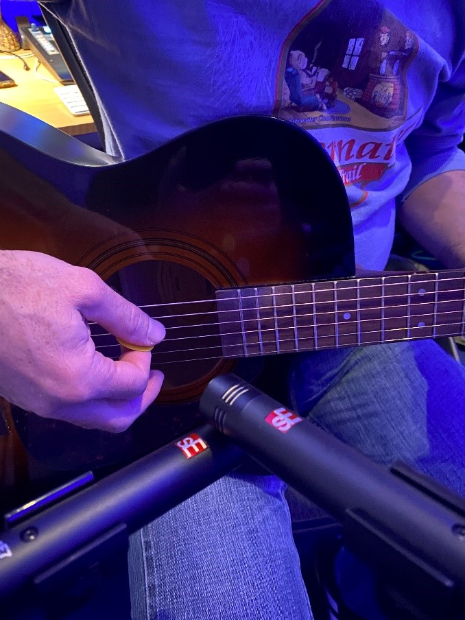 Closeup of someone playing acoustic guitar with microphone .