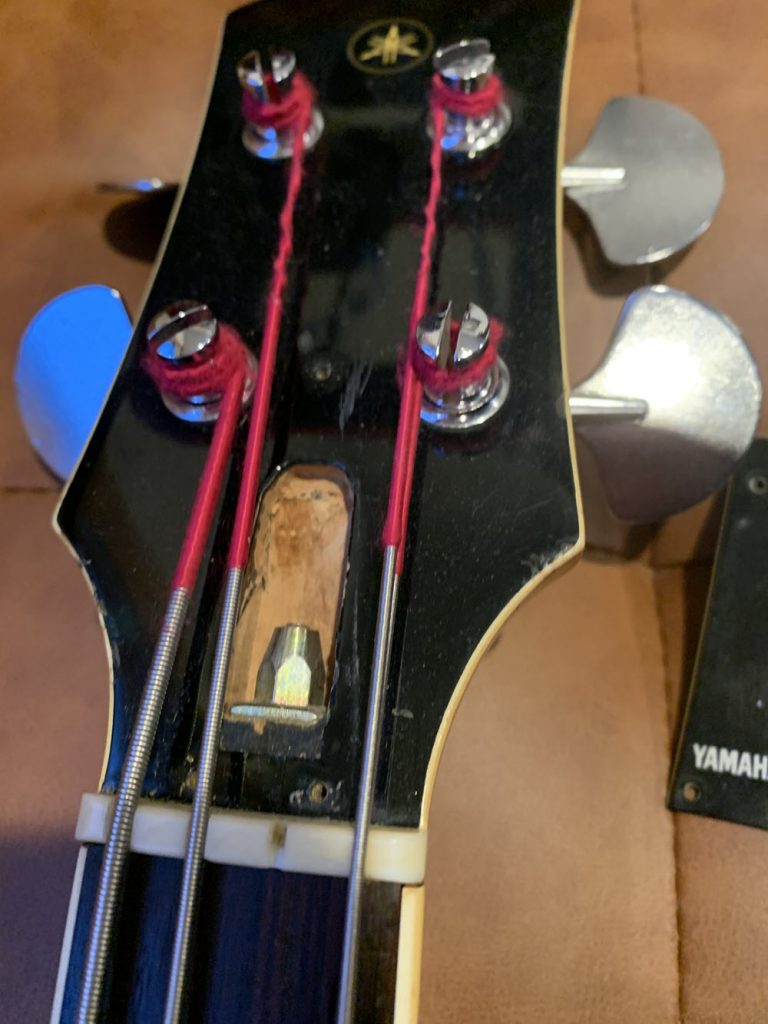 Closeup of bass guitar with truss cover removed and rod exposed.