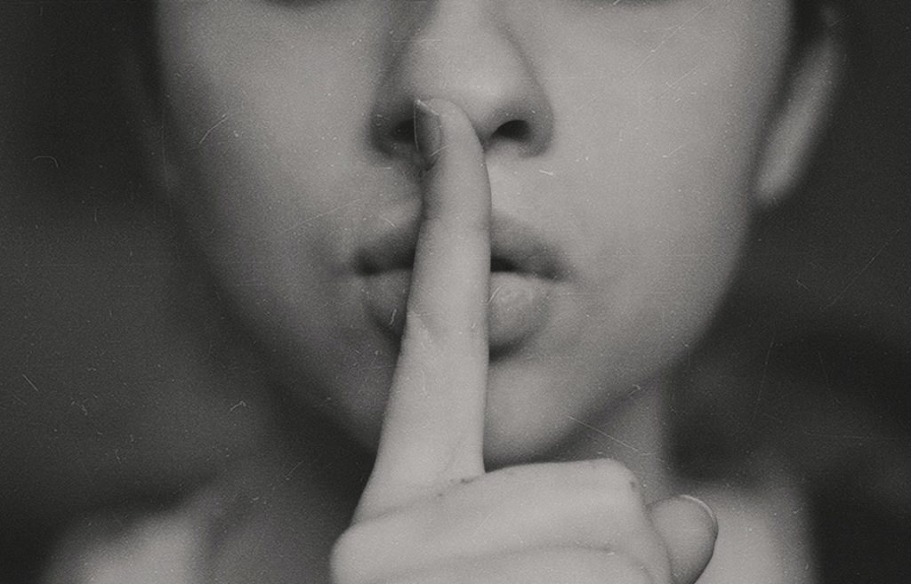 woman holding index finger to her lips