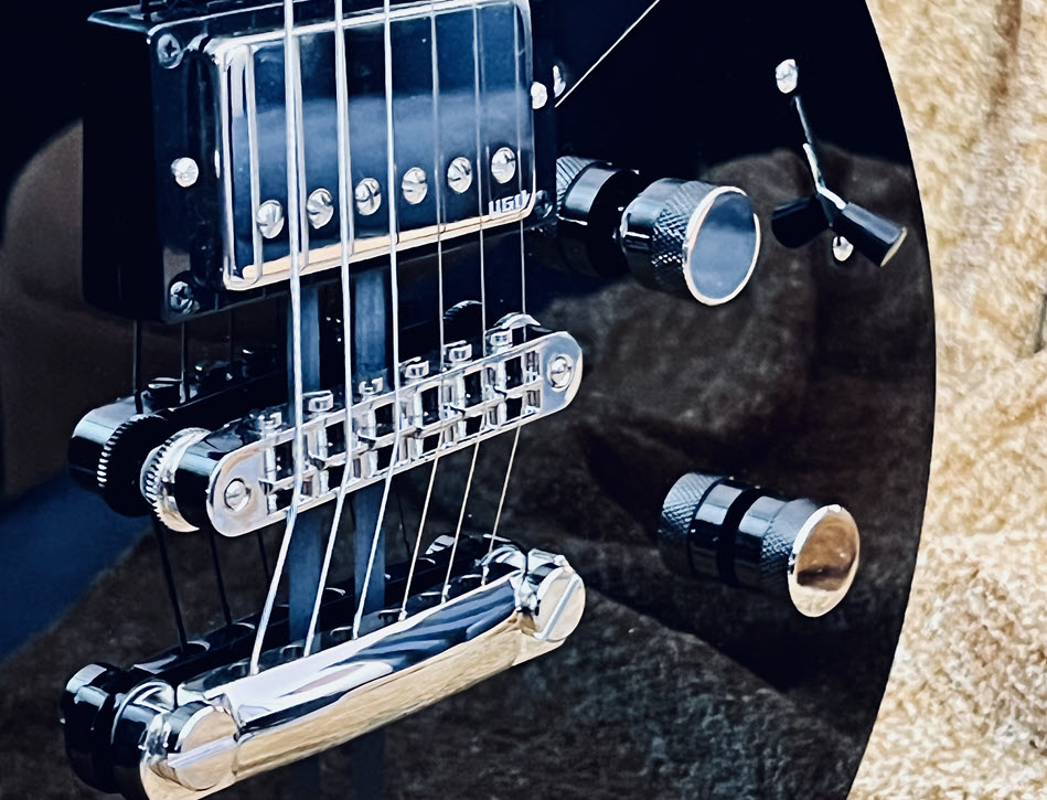 Closeup of the bridge and knobs on an electric guitar.