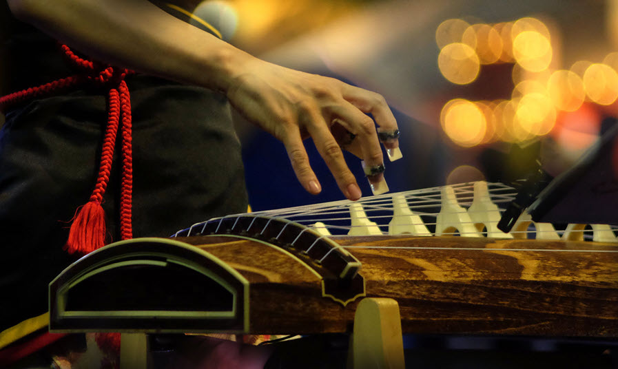 Closeup of someone's hand as they play a traditional string instrument.