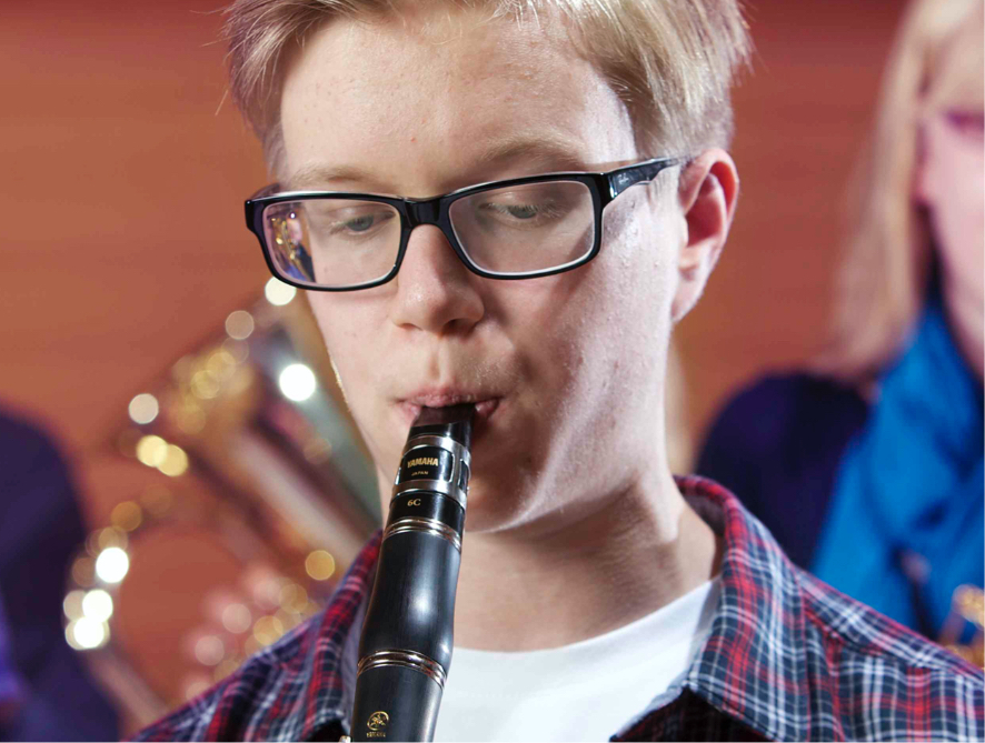 Teenager playing a clarinet in a school band.