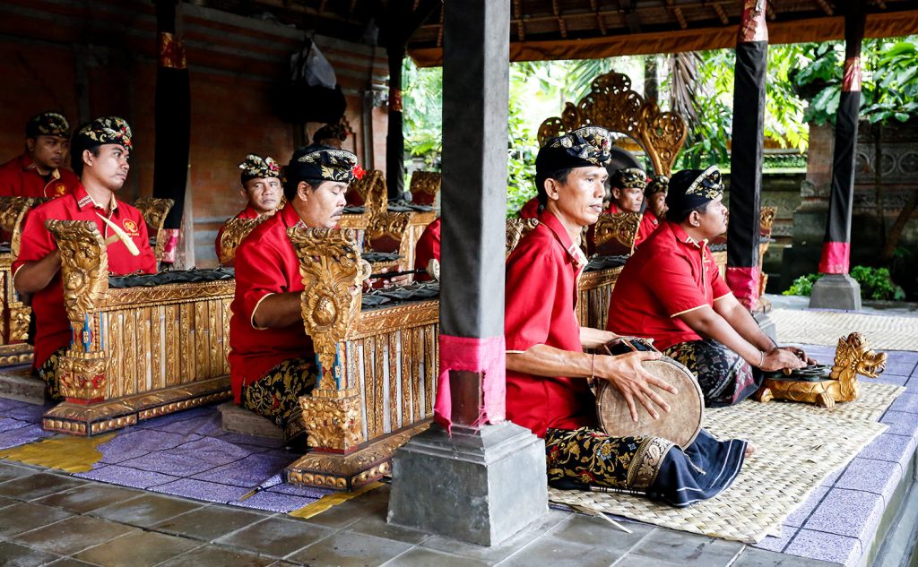 Group of men in traditional dress playing instruments in a pavilion.