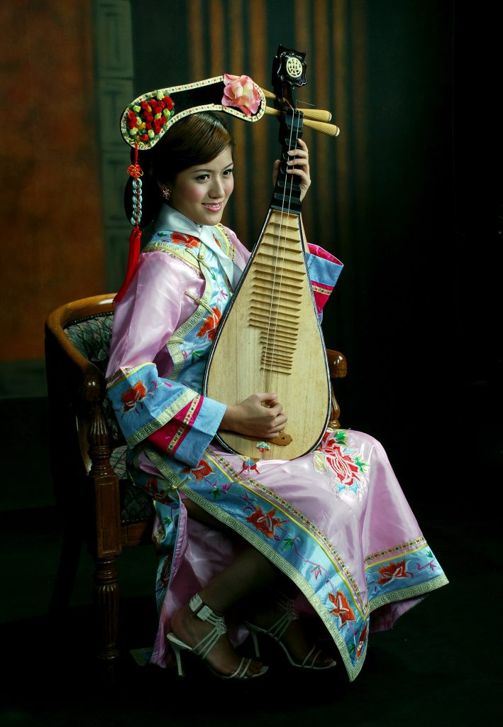 Woman in traditional dress holding a wooden stringed instrument.