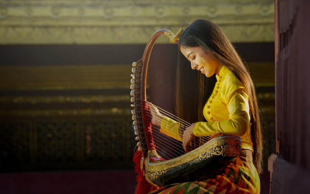 Young woman seen in profile playing a stringed instrument.