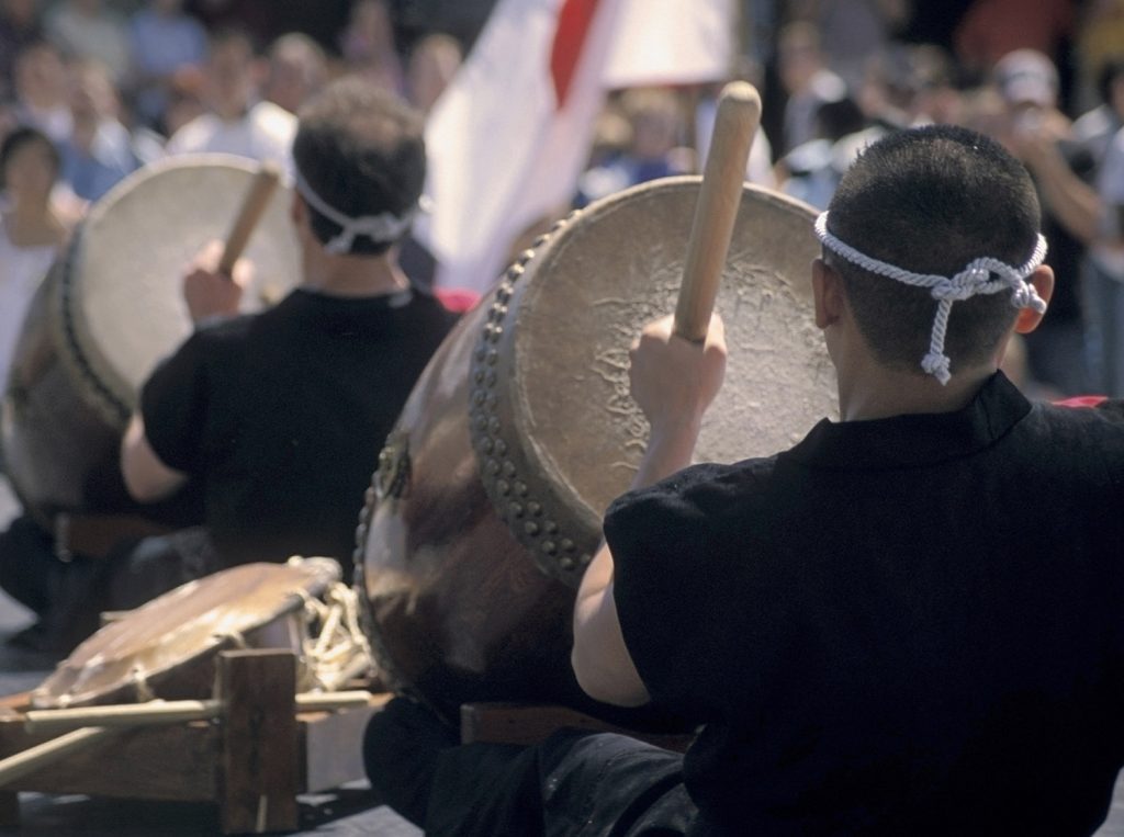 Group of men performing on large traditional drums.