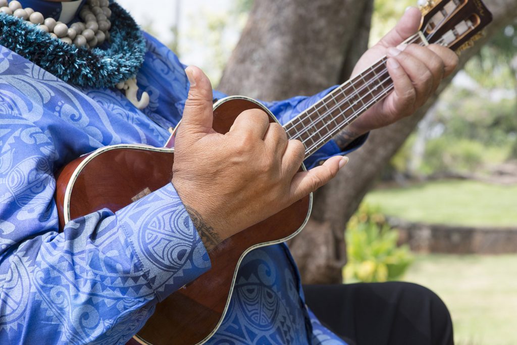 Closeup of man playing a ukelele.