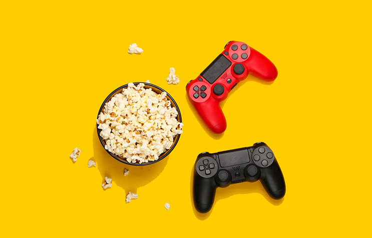 Bowl of popcorn and two game controllers as seen from above.