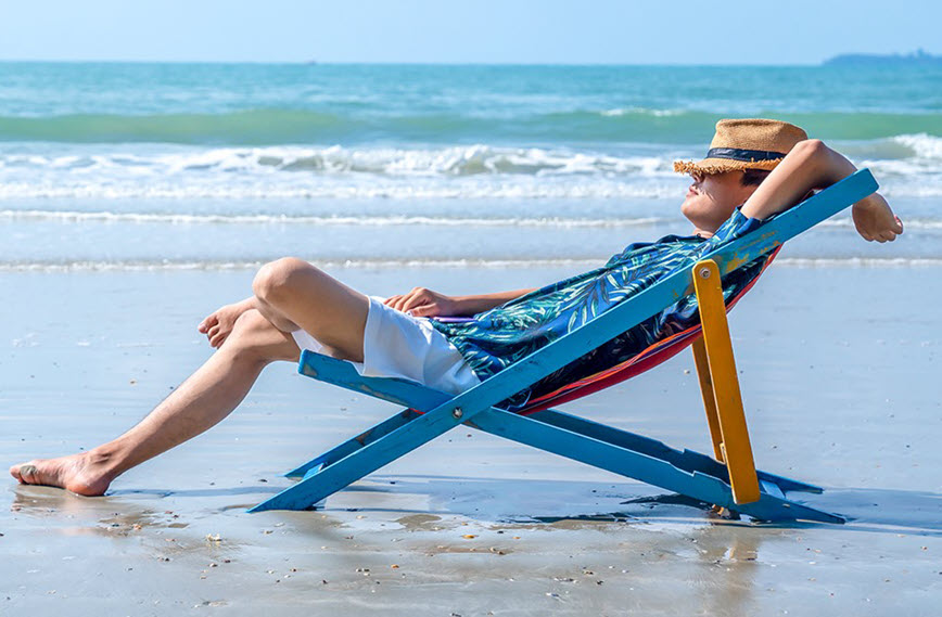 Man in lounge chair on beach.