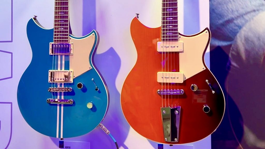 Closeup of the bodies of two electric guitars hanging on a wall.
