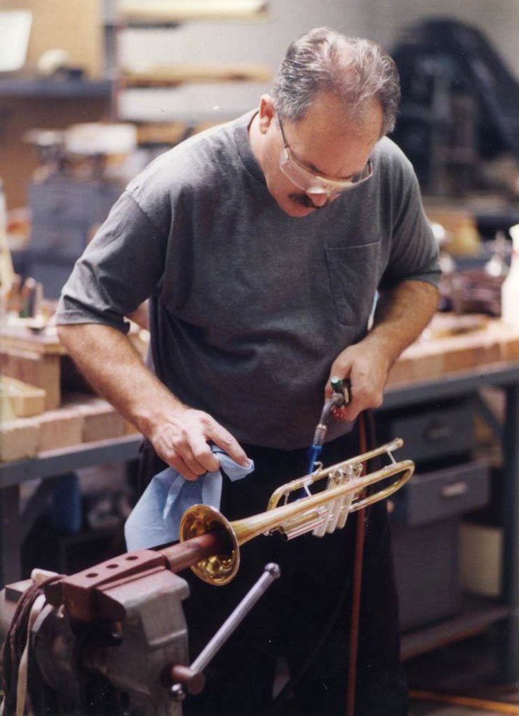 Man in workshop hand polishing a trumpet.