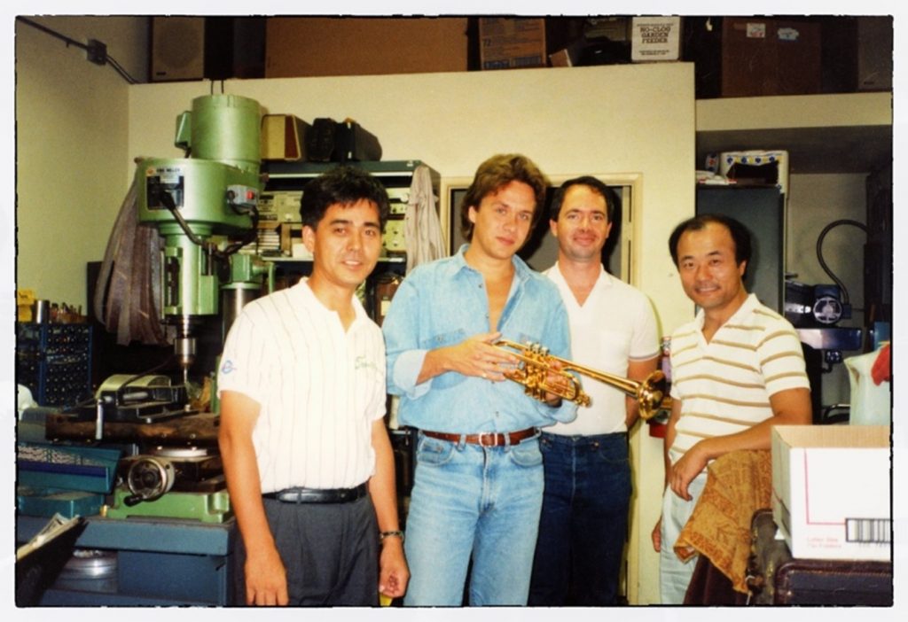 Four men standing side by side looking at camera in a workshop.