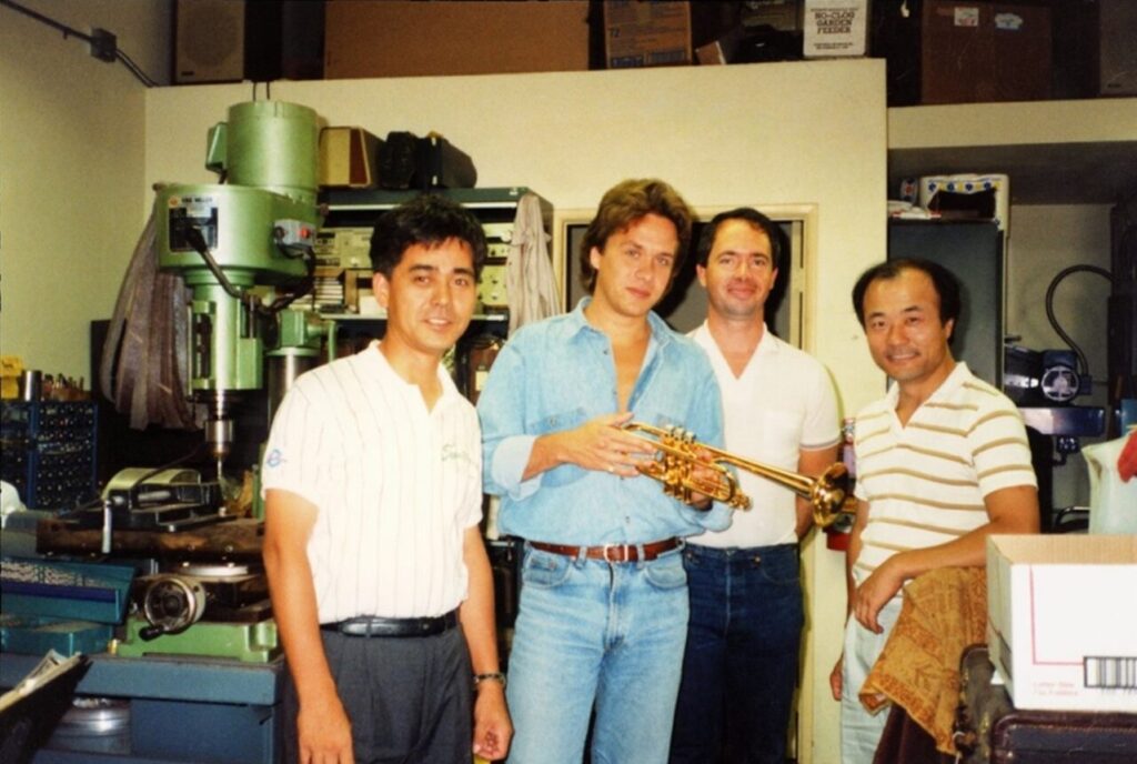 Four men standing side by side looking at camera in a workshop.