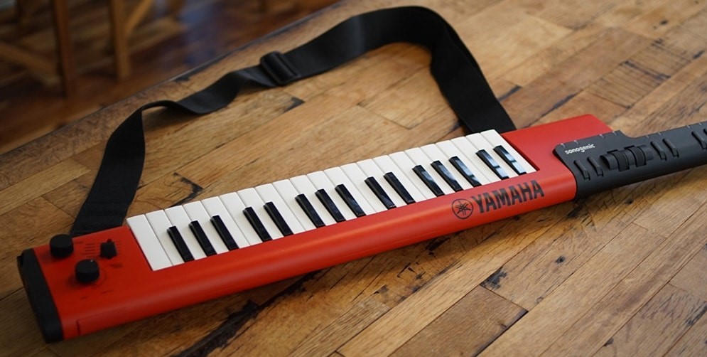 Electric music keyboard in a wearable guitar style holder with a neck and astrap.