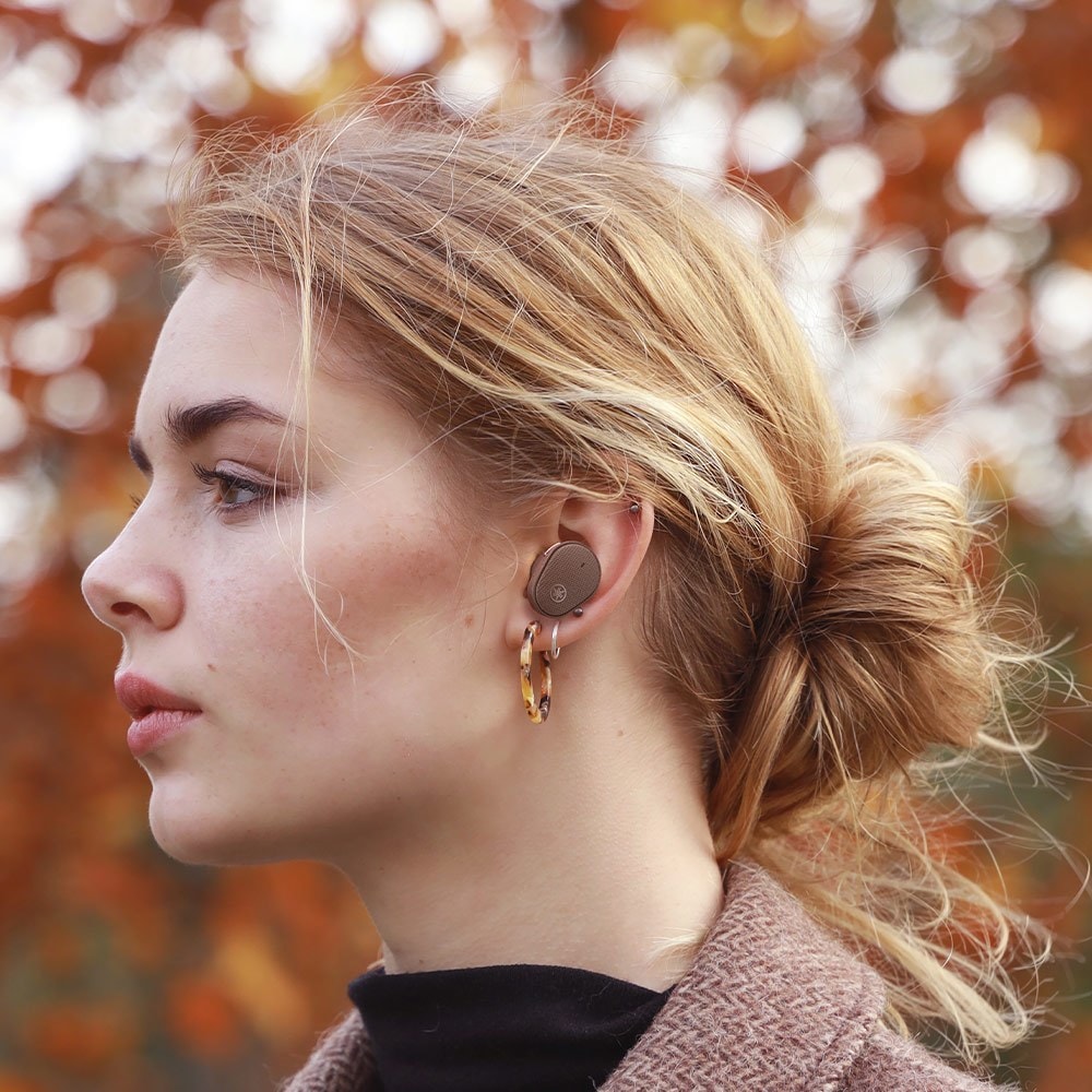 Young woman seen in profile with her hair pulled back and you can see a small earbud in her ear.
