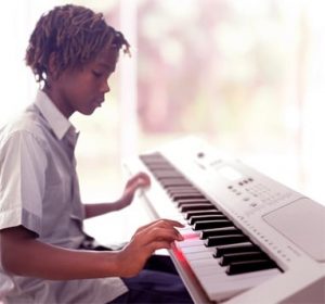 Middle school age child playing a full size electric keyboard in their home.