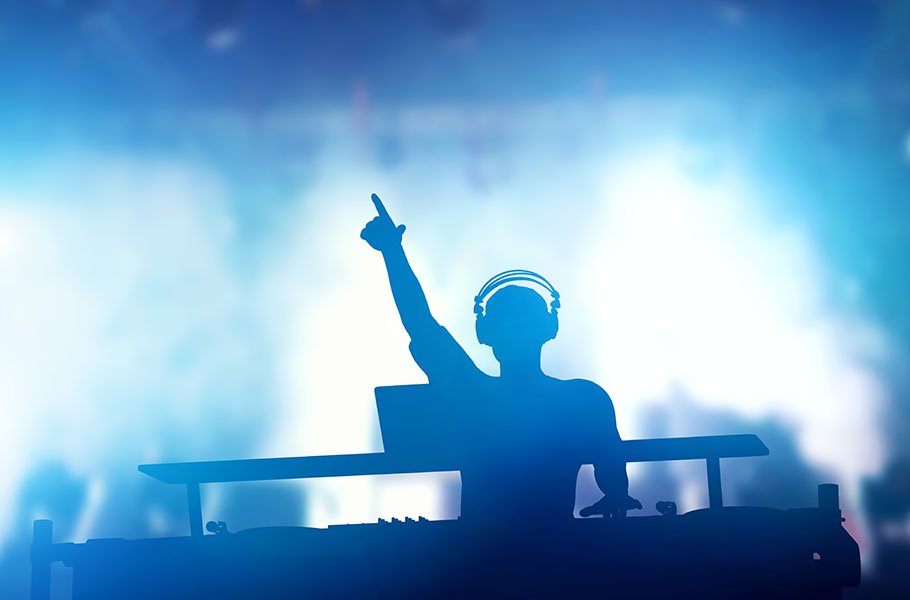 A DJ on stage seen in silhouette from the show lights.