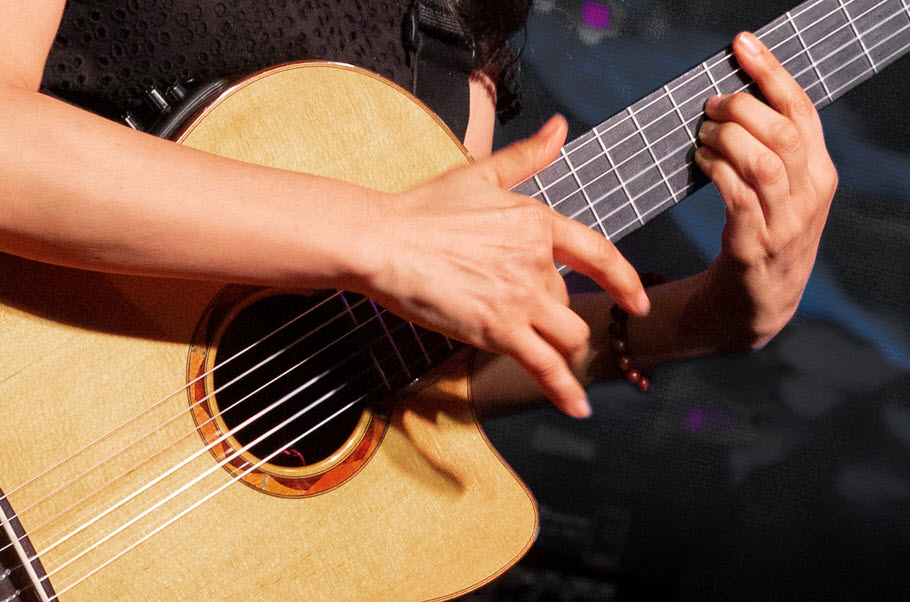 Closeup of hands playing an acoustic guitar.