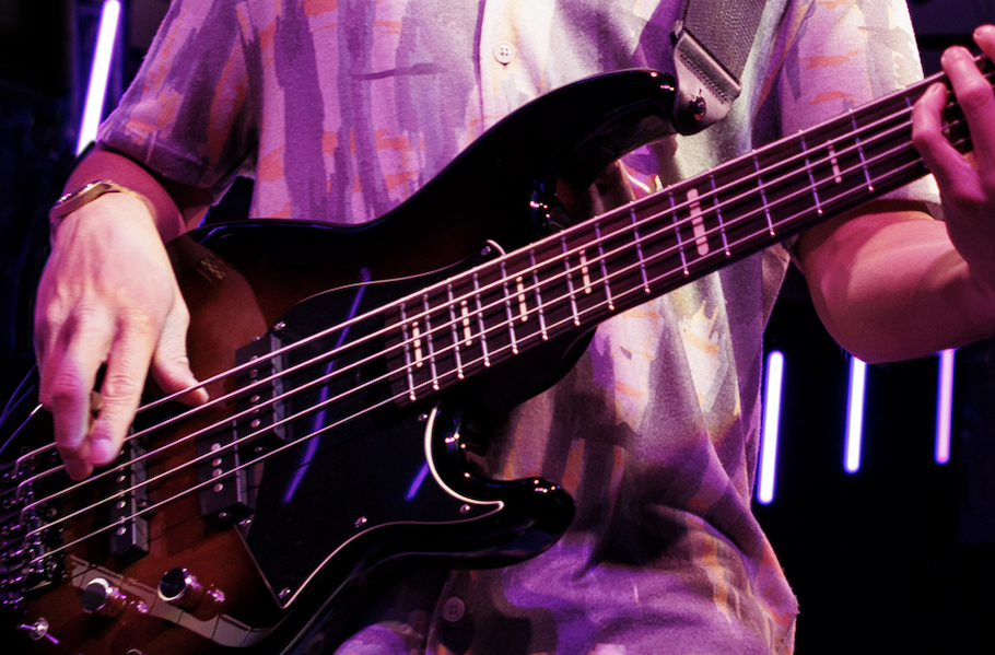 Closeup of a guy playing a bass guitar.