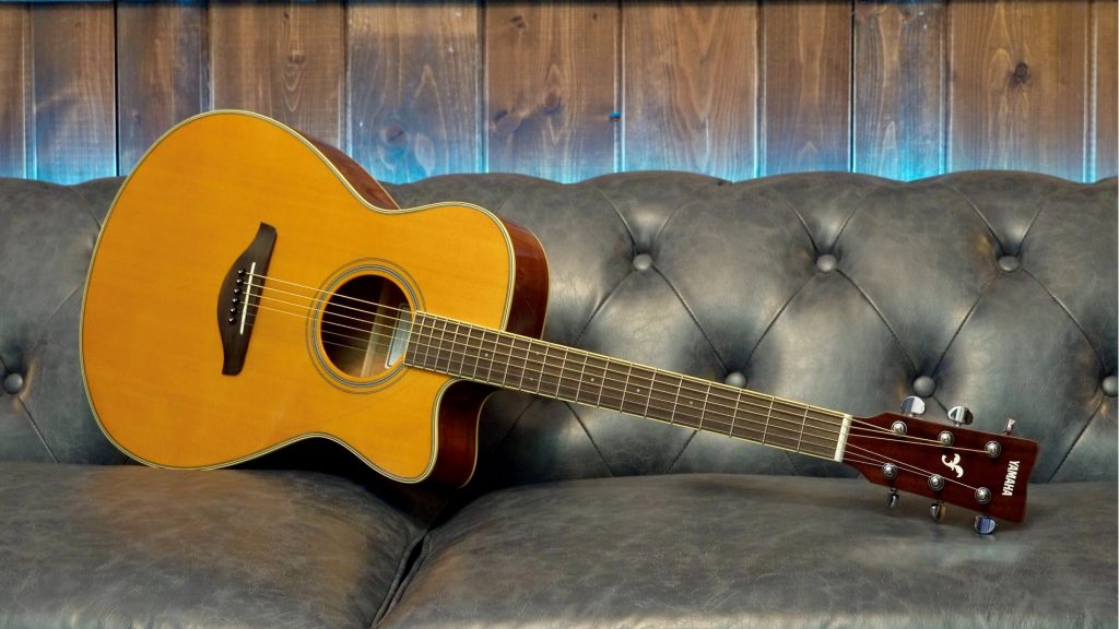 Guitar on its side on a leather couch.