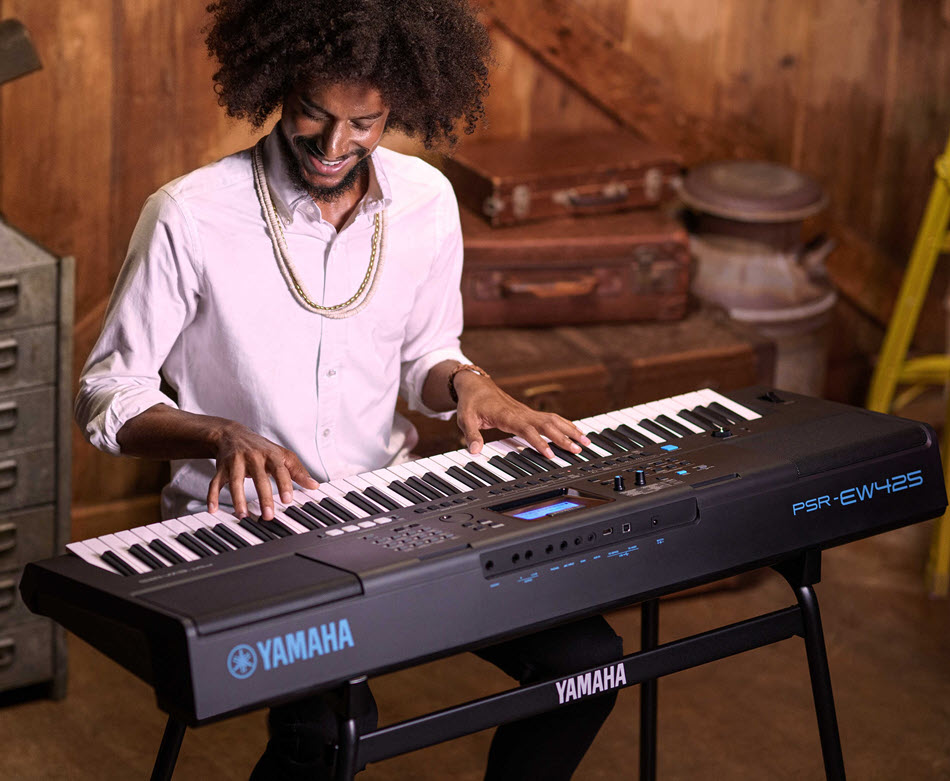 A guy is happily playing a Yamaha MODX+ music synthesizer in a studio setting.