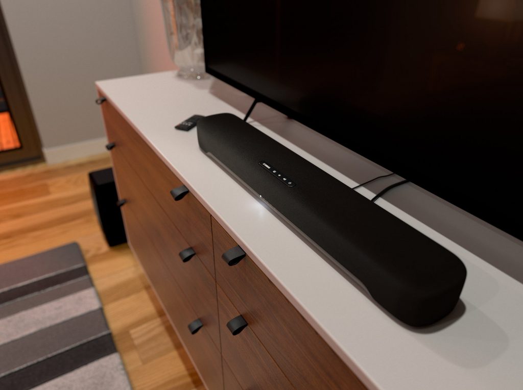 Long thin speaker on counter directly in front of flat screen's legs.