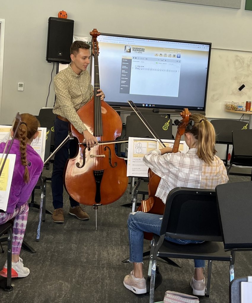 Music educator Tanner Otto playing bass with students