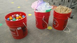 three buckets used for storage, holding egg shakers, scarves and drumsticks