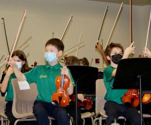 Edwin H. Greene Intermediate School orchestra students holding up their bows