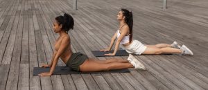two women outdoor doing yoga -- cobra pose
