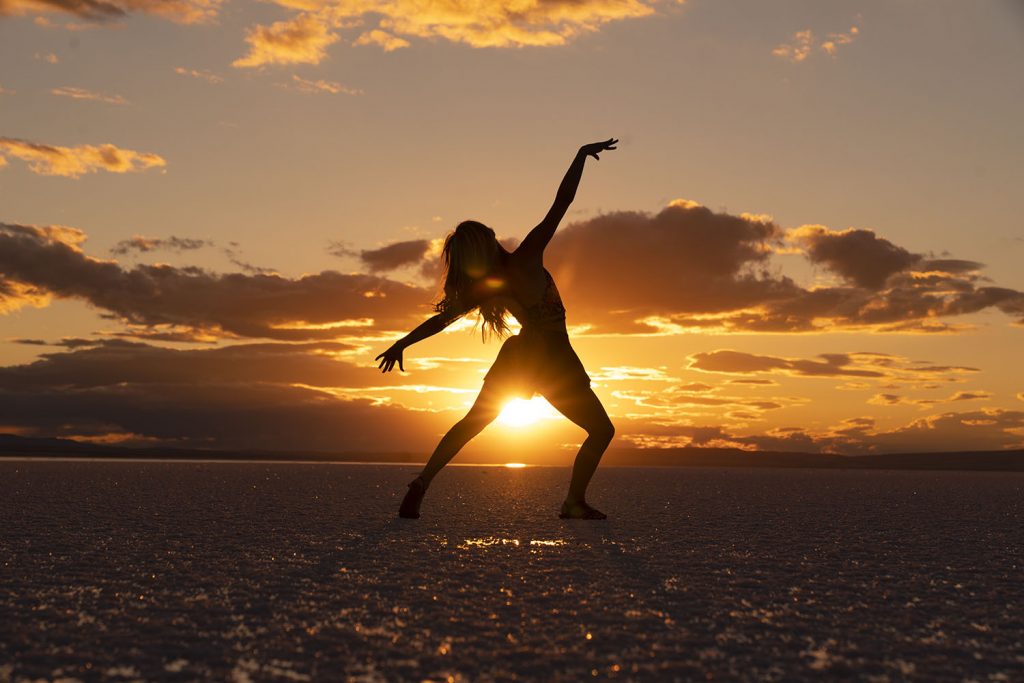 Woman dancing while the sunsets behind her.
