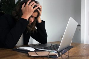 frustrated woman looking at laptop with hands on her head