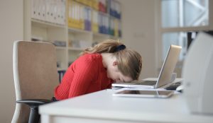frustrated woman with head down on her laptop