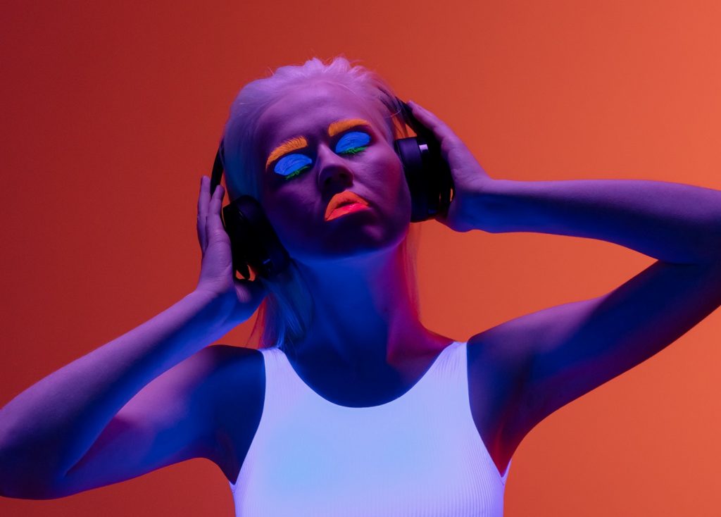 woman wearing headphones with face paintd with blue, orange and red paint