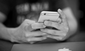 black and white close-up image of teenager's hands holding cell phone