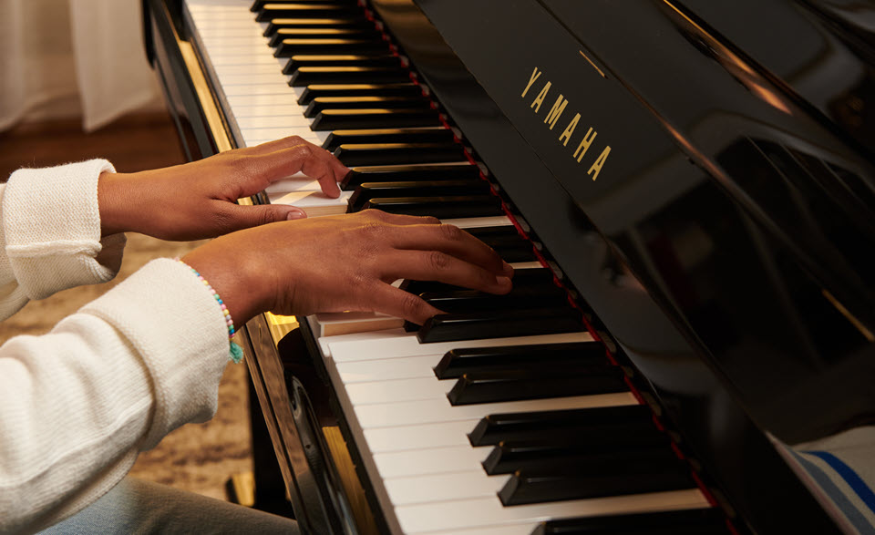 Closeup of someone's hands playing a Yamaha piano.
