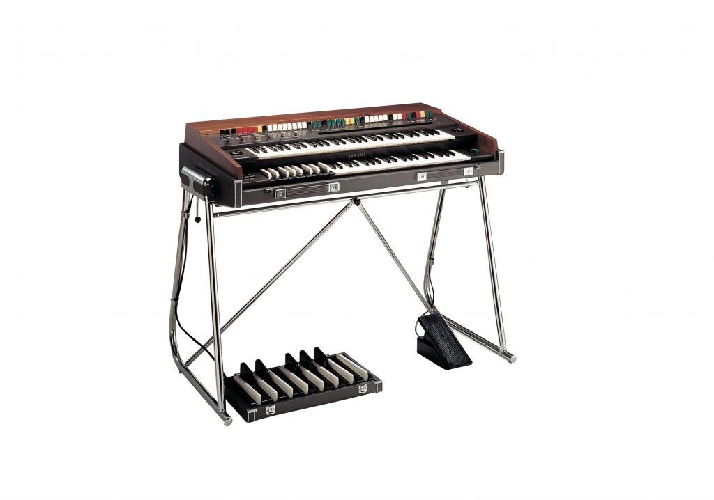 Electronic organ on a stand with a foot pedal.