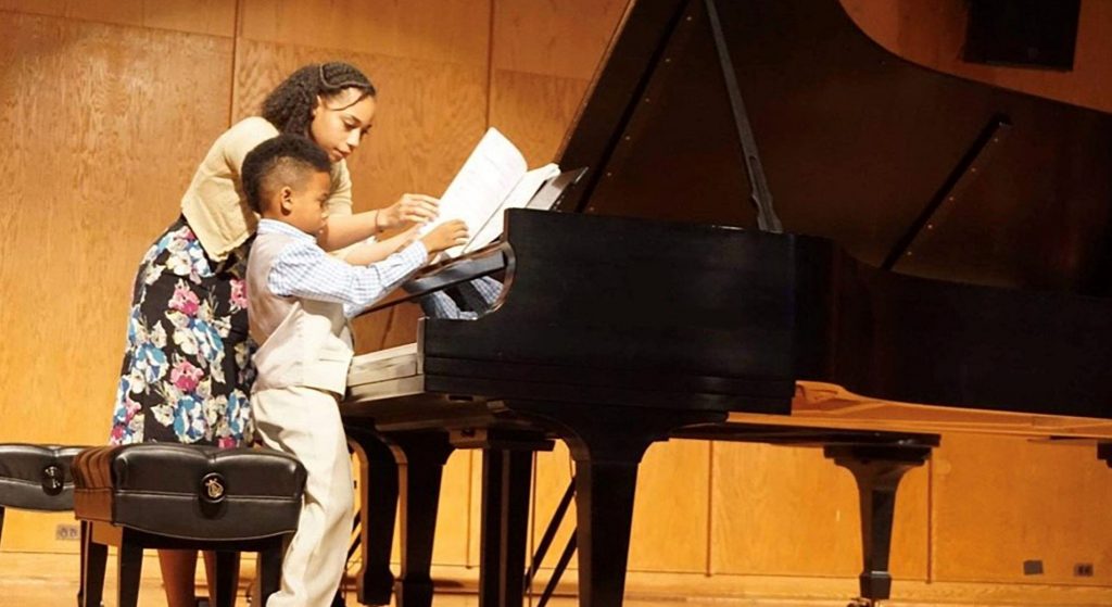 Dr. Leah N. Claiborne with young male student at piano