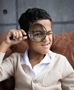 young boy holding a magnifying glass to his eye
