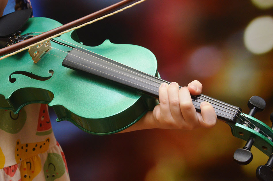 Closeup of someone playing a green violin/fiddle.