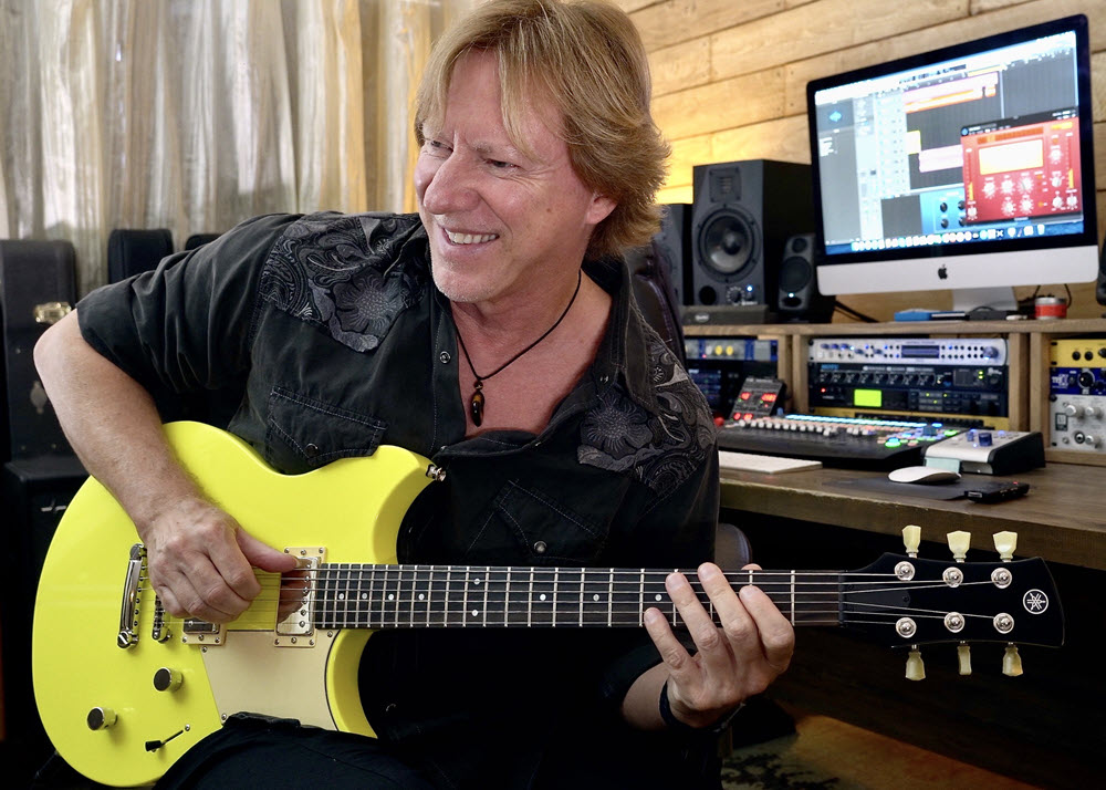 Author in his studio playing a yellow guitar.