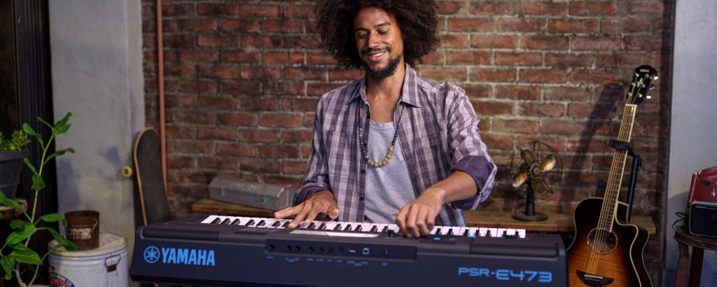 Smiling man playing a keyboard.
