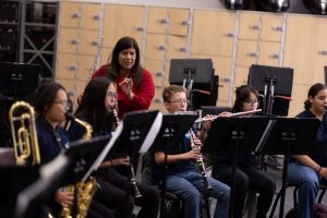 winds section rehearsing with director standing behind students holding a flute