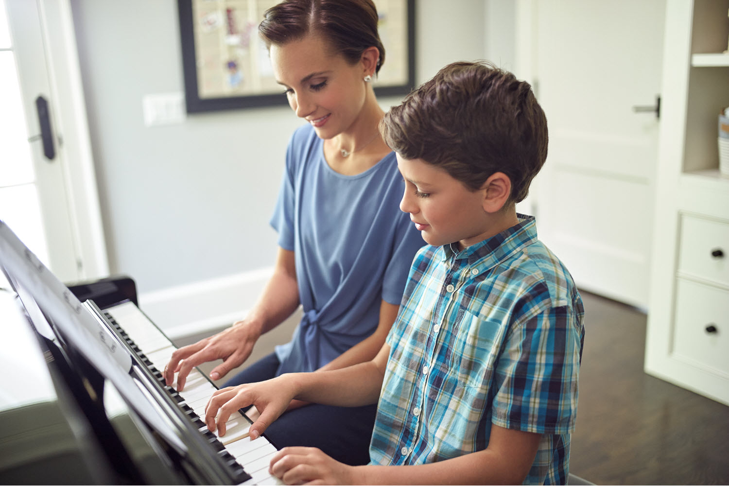 Mother and son side by side at piano.